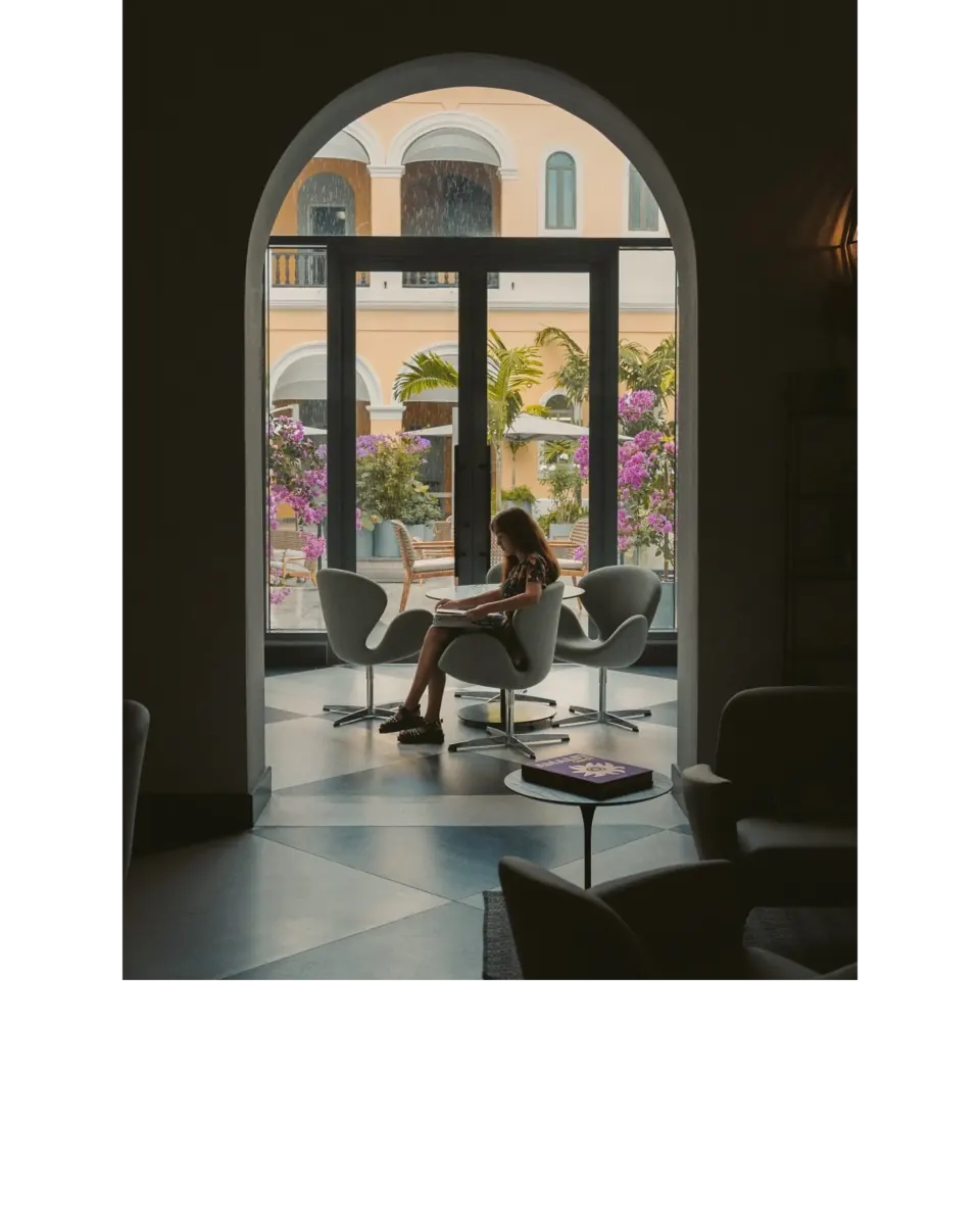 Person reading by an arched window overlooking a San Juan courtyard